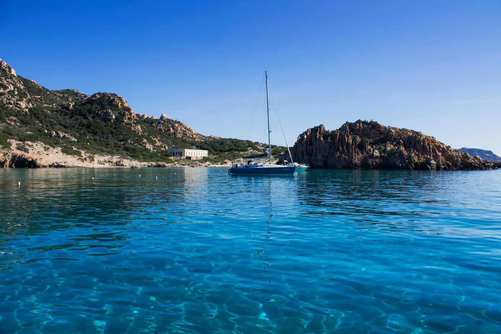 Voilier dans une crique turquoise de l'archipel de La Maddalena