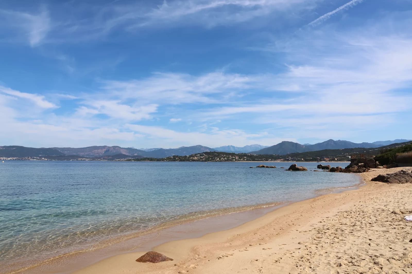 Longue plage de sable doré bordée d'une eau claire sur la Costa Smeralda